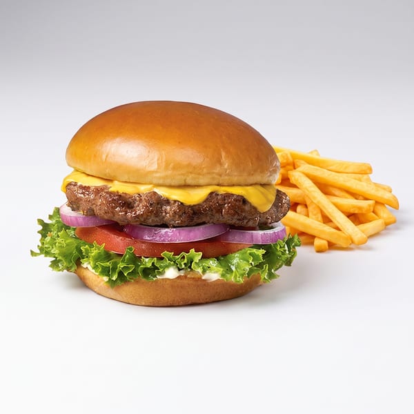 Cheeseburger with lettuce, tomato, onion, and a side of golden french fries on a white background.