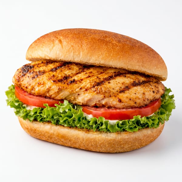 Grilled chicken sandwich with lettuce, tomato, and mayonnaise on a bun, isolated on white.